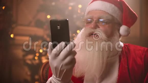 圣诞老人使用智能手机在举行会议时通过视频链接交谈圣诞老人和自拍相机视频的预览图