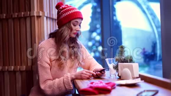 一个年轻漂亮的女孩独自坐在咖啡馆里看着他心烦意乱的电话视频的预览图