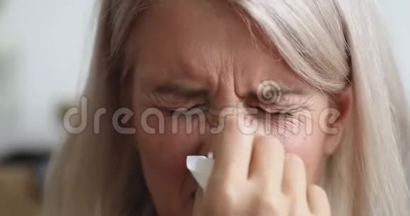患有过敏症的老妇人拿着组织打喷嚏近距离观看视频的预览图