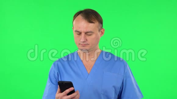 医生在手机上自拍然后在绿色屏幕上看照片视频的预览图