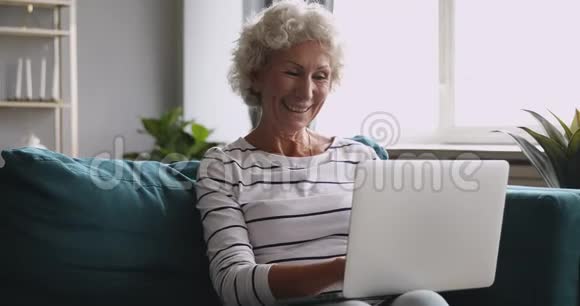 高兴兴奋的中年奶奶看着笔记本电脑屏幕视频的预览图