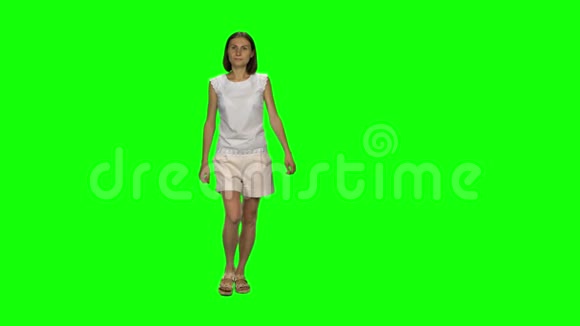 棕色头发和光滑发型的年轻女人平静地走在绿色的屏幕上铬钥匙4k射击前景视频的预览图