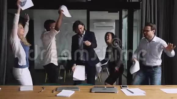 快乐的多种族同事在办公室跳舞在空中扔纸视频的预览图