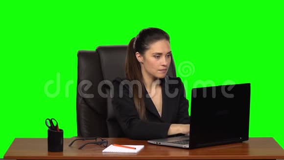女人热情地在笔记本电脑后面工作微笑着享受结果绿色屏幕慢动作视频的预览图