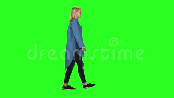 金发少女平静地走在绿色的屏幕背景上铬钥匙4k射击侧写视图视频的预览图
