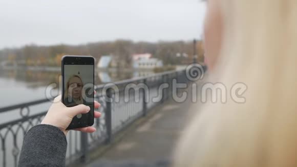 一个走在桥上的女人在视频聊天有影响力的人制造智能手机相机视频的预览图