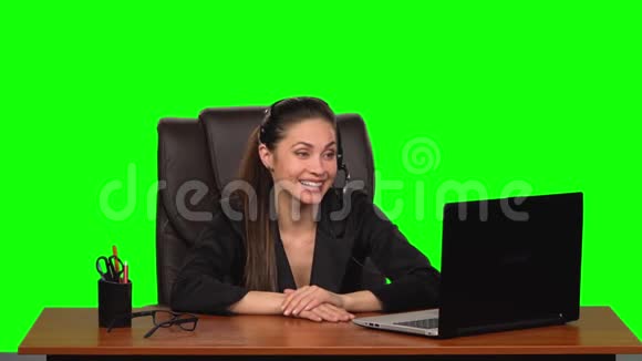 商务女性戴着耳机用网络摄像头说话带着喜悦的情绪看着笔记本电脑绿色屏幕慢动作视频的预览图