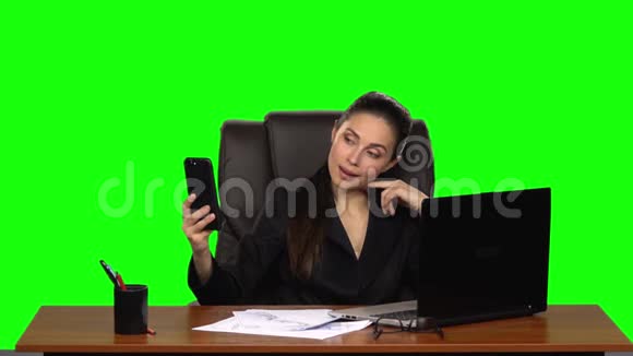职场女商人在手机上自拍然后兴高采烈地看着照片绿色屏幕工作室视频的预览图