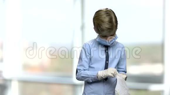 戴手术面罩的小男孩戴上橡胶手套视频的预览图