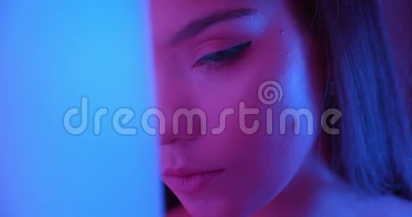霓虹灯中的特写女郎看着角落里的镜头淡淡的夜像调情的化妆眼睛视频的预览图