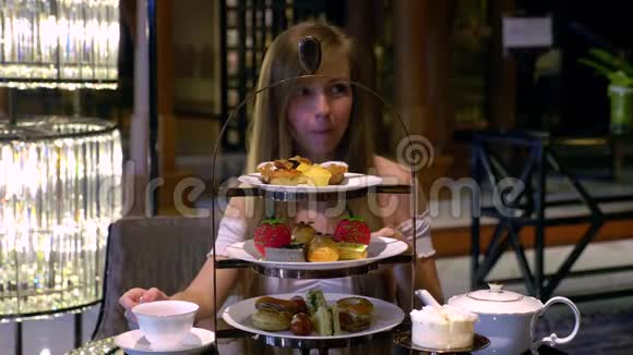 美丽的年轻女子在豪华餐厅吃小蛋糕和喝茶视频的预览图