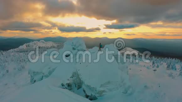 空中徒步旅行者站在美丽的冬季日落的雪山上视频的预览图