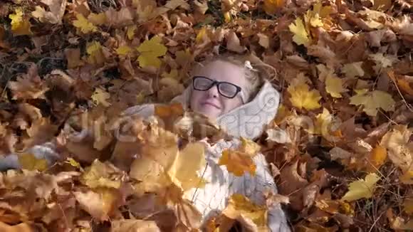 微笑的少女躺在秋天落叶上视频的预览图