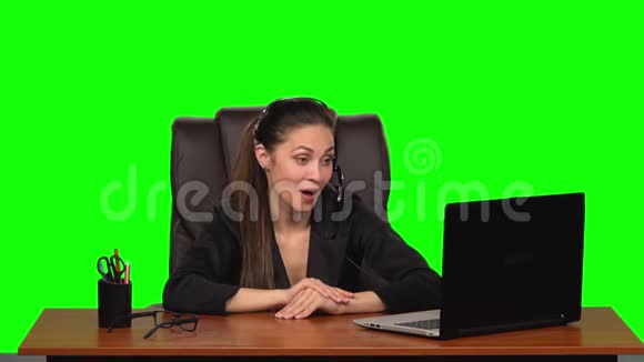 商务女性戴着耳机用网络摄像头说话带着喜悦的情绪看着笔记本电脑绿色屏幕慢动作视频的预览图