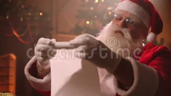 圣诞老人的肖像在圣诞前夕卷起一幅卷轴检查准备礼物的儿童名单视频的预览图