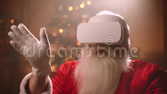现代圣诞老人坐在椅子上用虚拟现实技术给孩子们买礼物送礼物视频的预览图