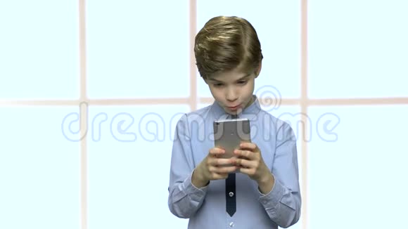 英俊的小男孩用智能手机视频的预览图