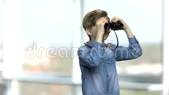 微笑的白种人男孩透过望远镜看视频的预览图