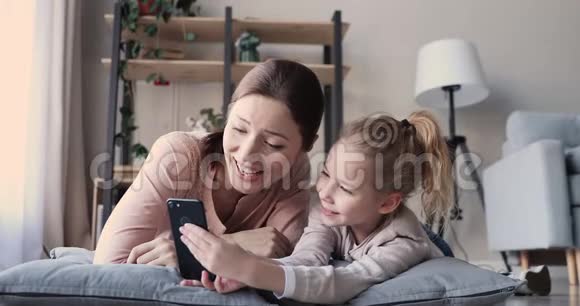 妈妈和小女儿玩游戏视频打电话给智能手机视频的预览图