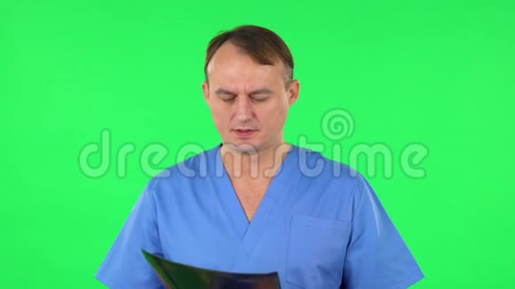 男医生穿着蓝色外套用x光检查快照并解释绿色屏幕视频的预览图
