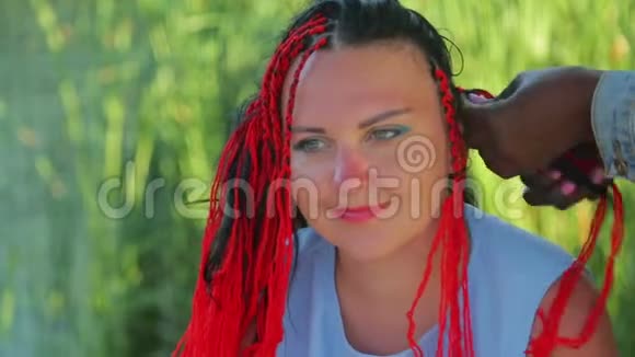 一个年轻的犹太女人用红线编织辫子一个深色皮肤的女孩视频的预览图
