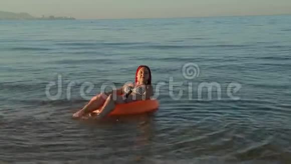 穿着泳衣在海上游泳的红发女子在游泳圈晒太阳视频的预览图