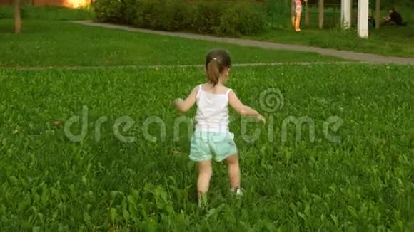 夏天快乐的孩子在草地上奔跑在绿草上奔跑开朗的小女孩跑过田野幸福的概念视频的预览图