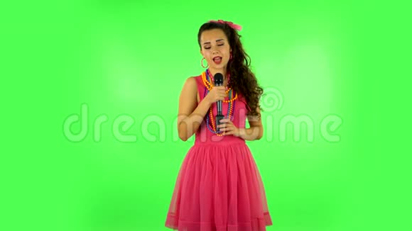 迷人的女孩唱成麦克风并移动到音乐的节拍绿色屏幕视频的预览图
