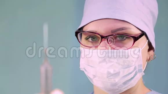 戴着医用口罩的女医生手里拿着注射器视频的预览图