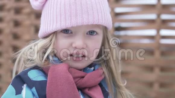 一个戴着粉红色帽子的漂亮小女孩在散步时扔雪球视频的预览图