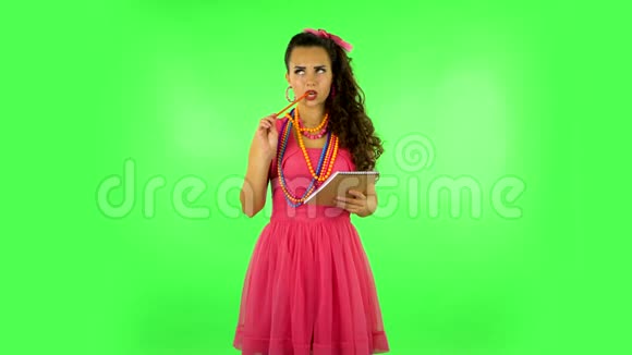女孩站着思考然后用铅笔在笔记本上写然后生气绿色屏幕视频的预览图