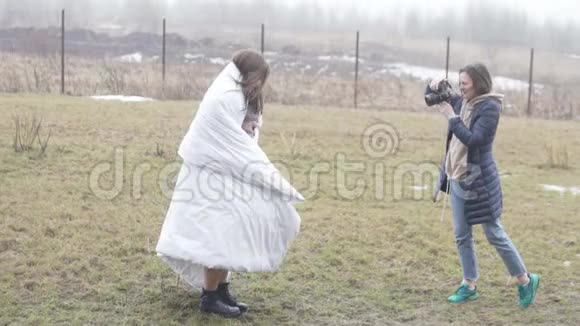 一位女摄影师正在外面用毯子给模特拍照视频的预览图