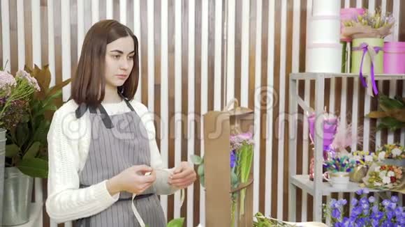 年轻女子花店在车间或商店里装饰鲜花和绿叶的礼品视频的预览图