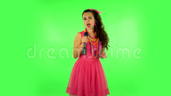 迷人的女孩唱成麦克风并移动到音乐的节拍绿色屏幕视频的预览图
