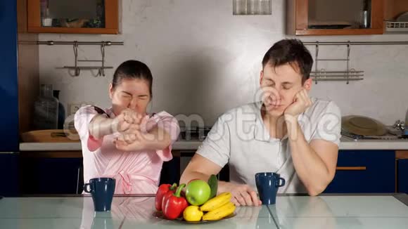 一对夫妇坐在餐桌旁打哈欠睡着了视频的预览图
