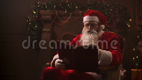 一位美丽的圣诞老人坐在椅子上背景是一棵装饰好的圣诞树上面有一个花环上面写着视频的预览图
