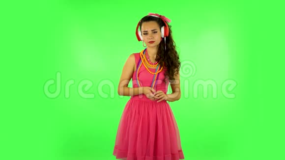 穿着红色大耳机在绿色屏幕上跳舞唱歌的女孩视频的预览图