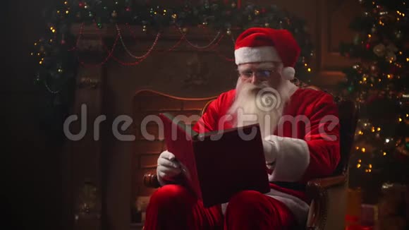 圣诞老人在圣诞前夜在椅子上看书视频的预览图