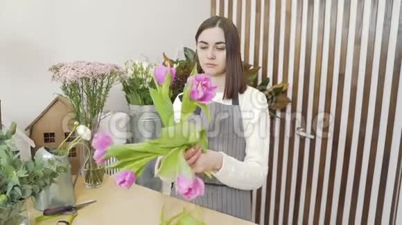 年轻女子花商在一家花店或作坊里创作一束郁金香视频的预览图