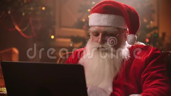 在一种神奇的气氛中圣诞老人用笔记本电脑工作并在视频的预览图