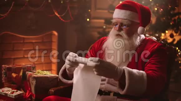 圣诞老人在圣诞前夜卷起一幅卷轴检查准备礼物的儿童名单太棒了视频的预览图