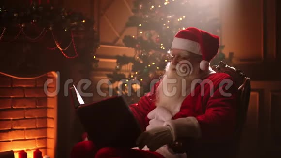 圣诞老人魔法房坐在家里的一束光中背景是壁炉和圣诞树视频的预览图