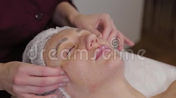 专业美容师女性为美容院客户做面部按摩视频的预览图
