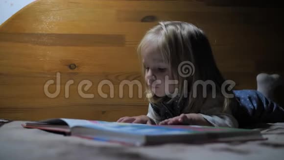 小女孩在一盏灯的灯光下翻阅一本书的书页视频的预览图