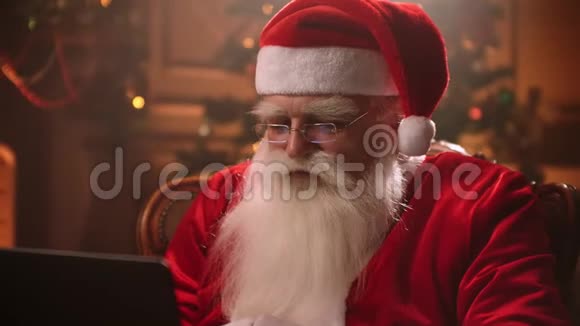 白胡子的圣诞老人坐在椅子上从事网上银行业务查看他们的帐户和电子邮件视频的预览图