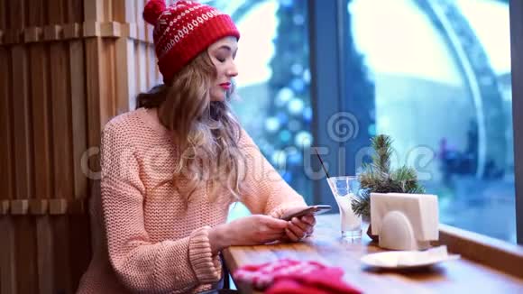 一个年轻漂亮的女孩独自坐在咖啡馆里看着他心烦意乱的电话视频的预览图