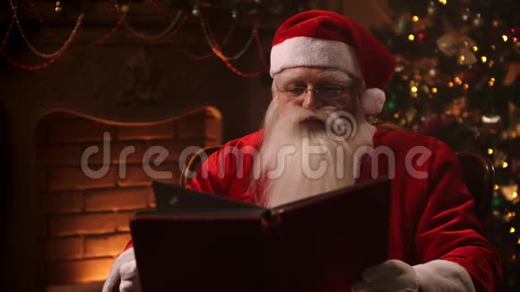 一个留着白胡子的男人穿着圣诞老人的西装坐在椅子上背着一棵装饰好的圣诞树视频的预览图