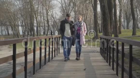 在阳光明媚的秋日轻松的白种人男女沿着公园小巷散步夫妻幸福美满视频的预览图