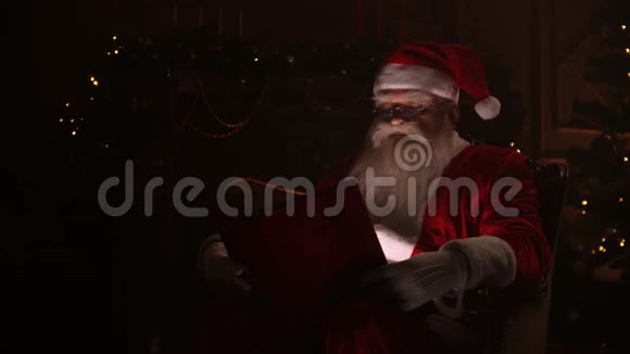 圣诞老人坐在特别装饰的房间里读着一本神奇的闪亮的书节日和庆祝活动圣诞节视频的预览图
