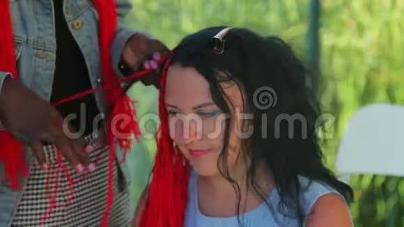 一个年轻的犹太女人用红线编织辫子一个皮肤黑的女孩视频的预览图